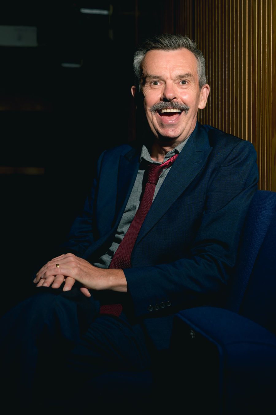 Mark Flynn, founder of The AI Boardroom, smiling, in a navy suit and red tie